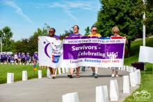 four women march behind a banner for American Cancer Society Relay for Life