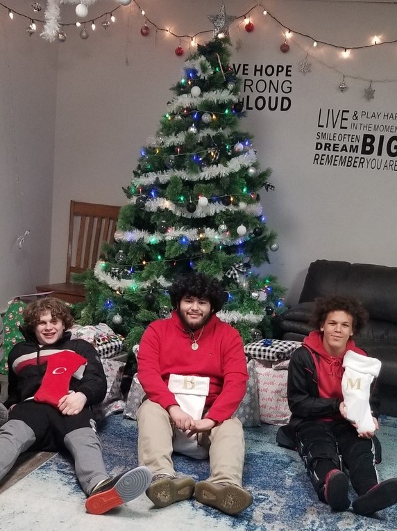 boys holding gifts in front of Christmas tree