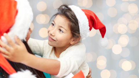 A child and volunteer wearing santa hats