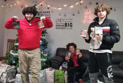 Young adult males hold gifts from OHB's Project Christmas Joy