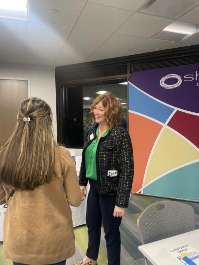 Two women networking in front of the SHARE Omaha backdrop